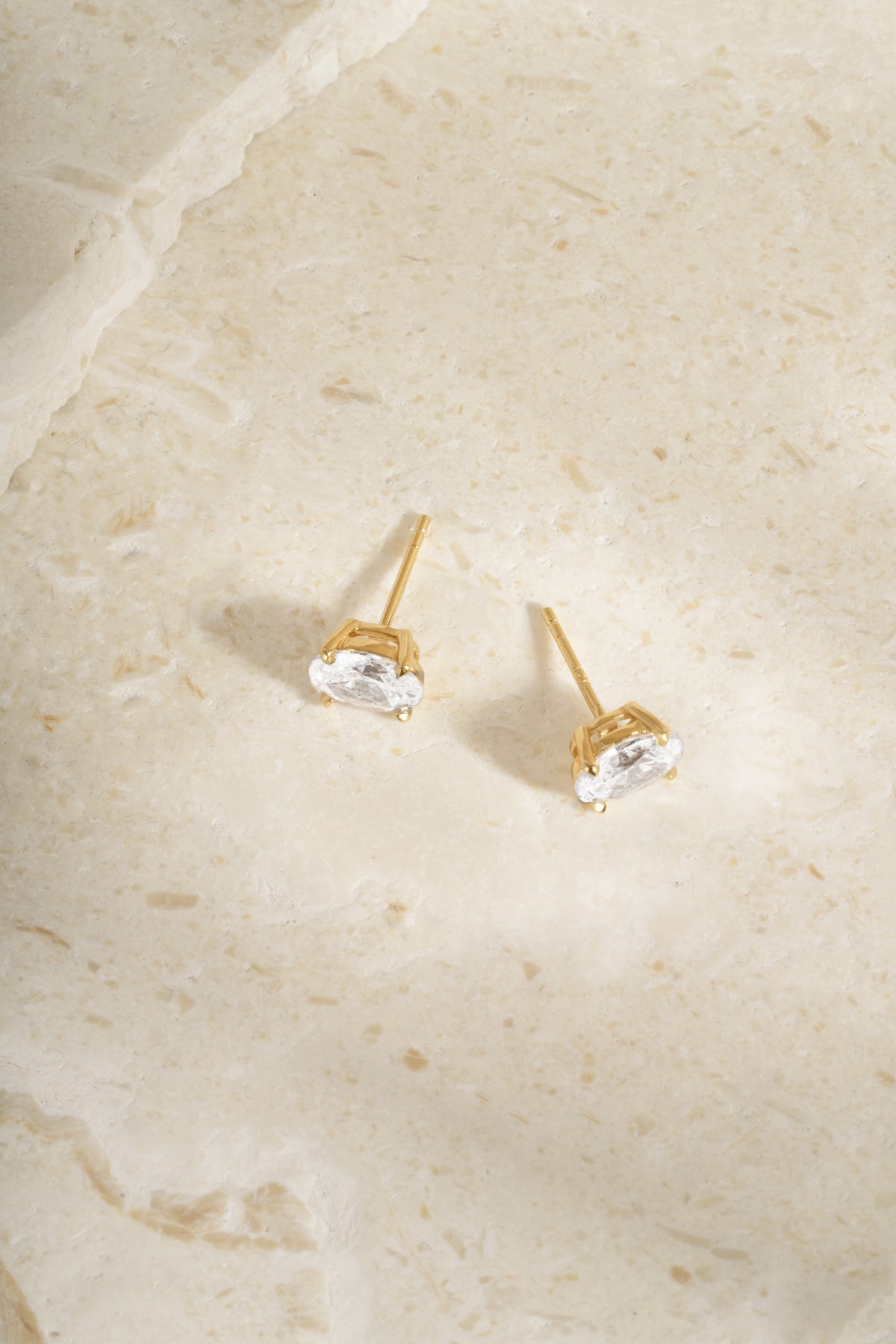 Gold 4x6mm oval studs from above, showing their posts and open four-prong settings.