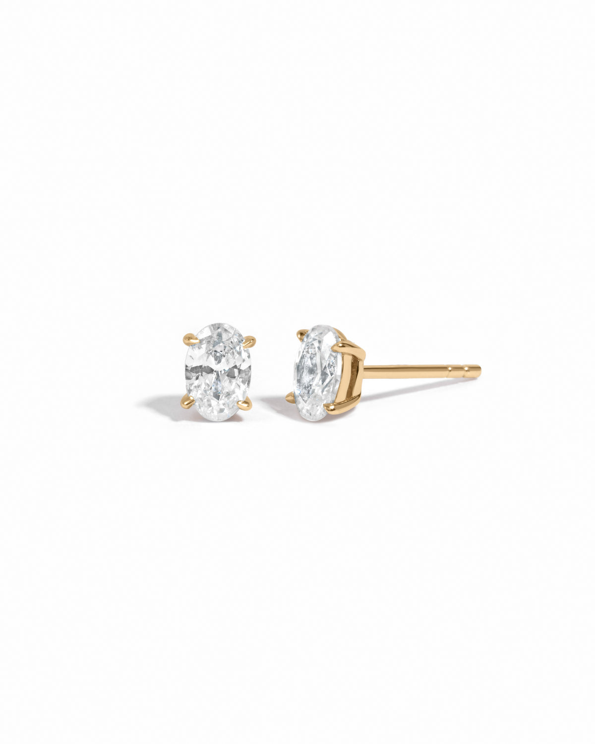 Gold 4x6mm oval CZ stud earrings shown from the front and side on white.