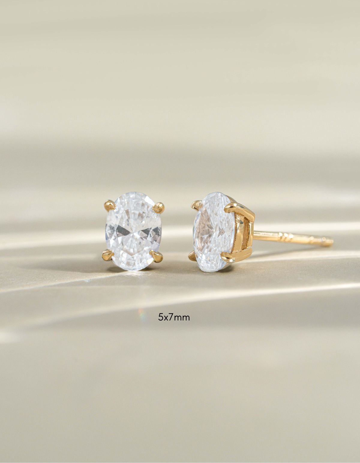 Gold 5x7mm oval stud earrings by Sami Jewels, front view showing smooth polished surface and classic jewelry style.