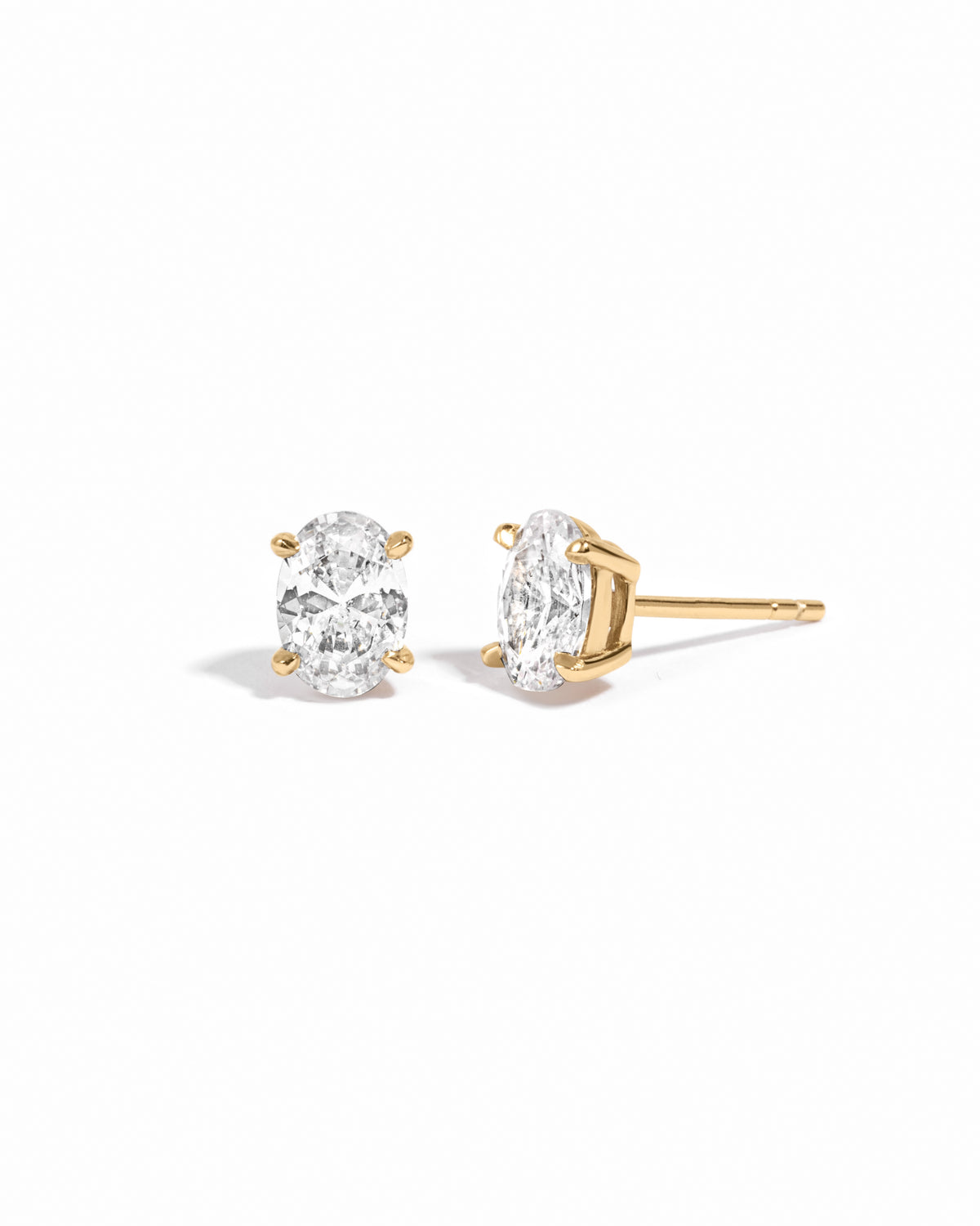 Gold 5x7mm oval CZ stud earrings shown from the front and side on white.