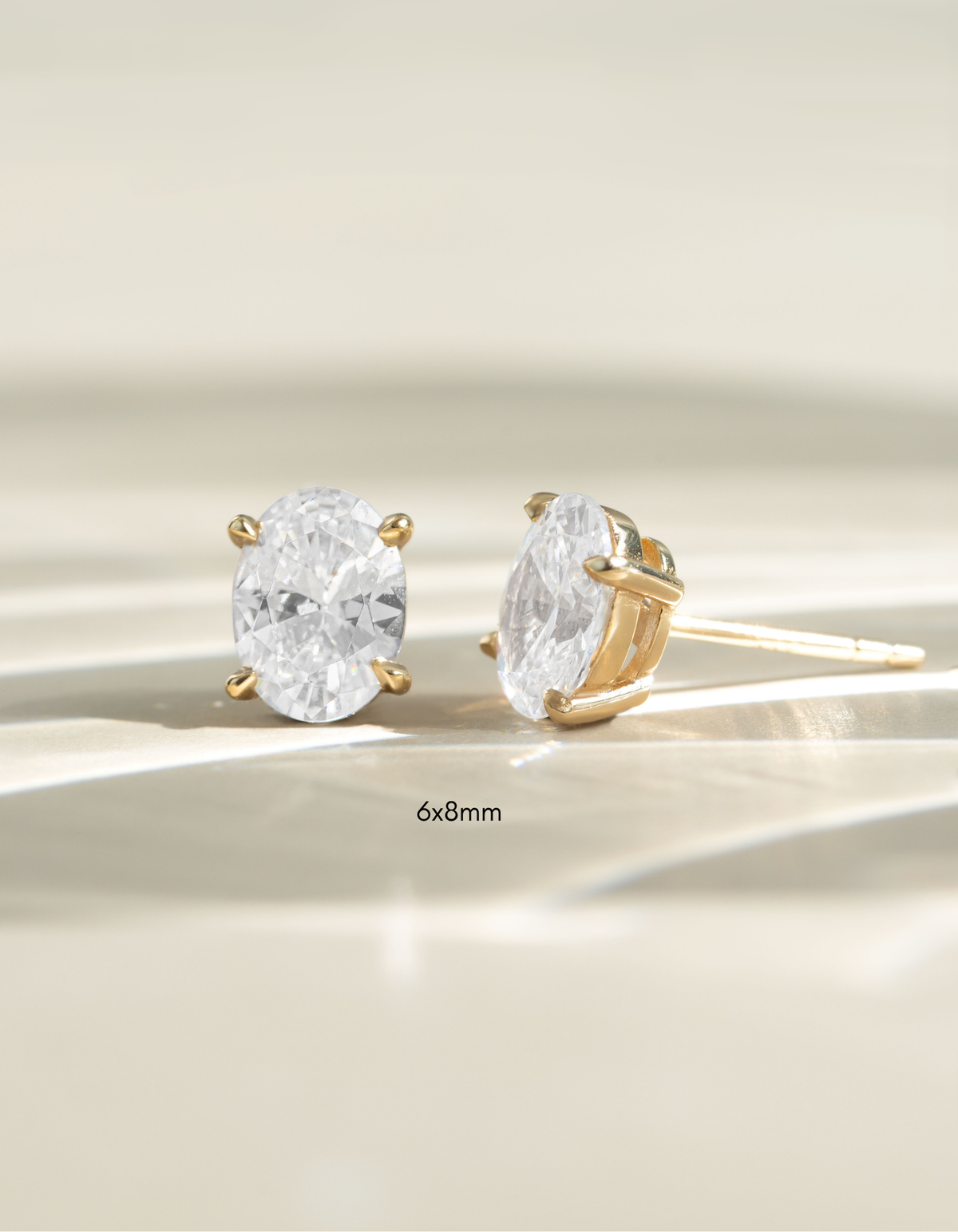 Gold 6x8mm oval stud earrings by Sami Jewels, front view showcasing smooth polished surface and classic stud design.
