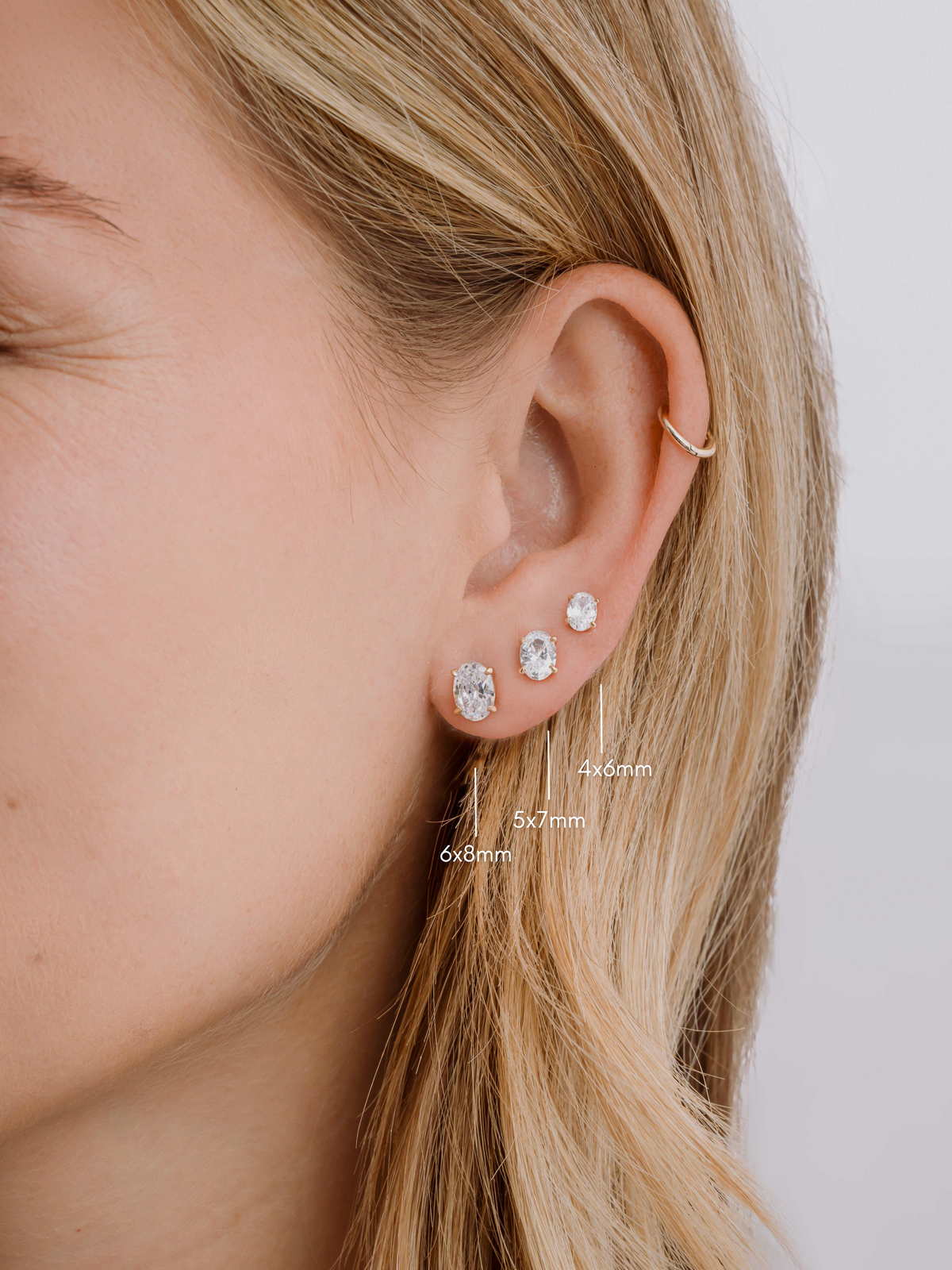 Size guide showing 4x6mm, 5x7mm and 6x8mm oval studs together on a model's ear.