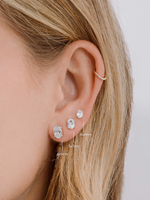 Silver oval studs in three sizes worn together on a model's ear.