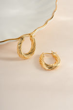 Gold oval textured hoop earrings by Sami Jewels, shown from an angled view highlighting the textured surface.