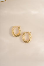 Gold oval textured hoop earrings from Sami Jewels, shown in a side view highlighting their elegant design and smooth finish.