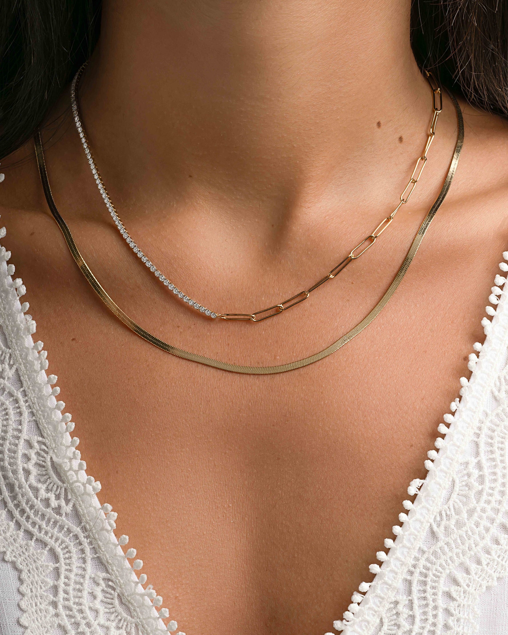 Gold tennis and paperclip necklace stack from Sami Jewels featuring layered jewelry on a model.