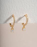 Close-up of gold Pavé Charm Huggies earrings by Sami Jewels with sparkling pave detailing and small charm accents.