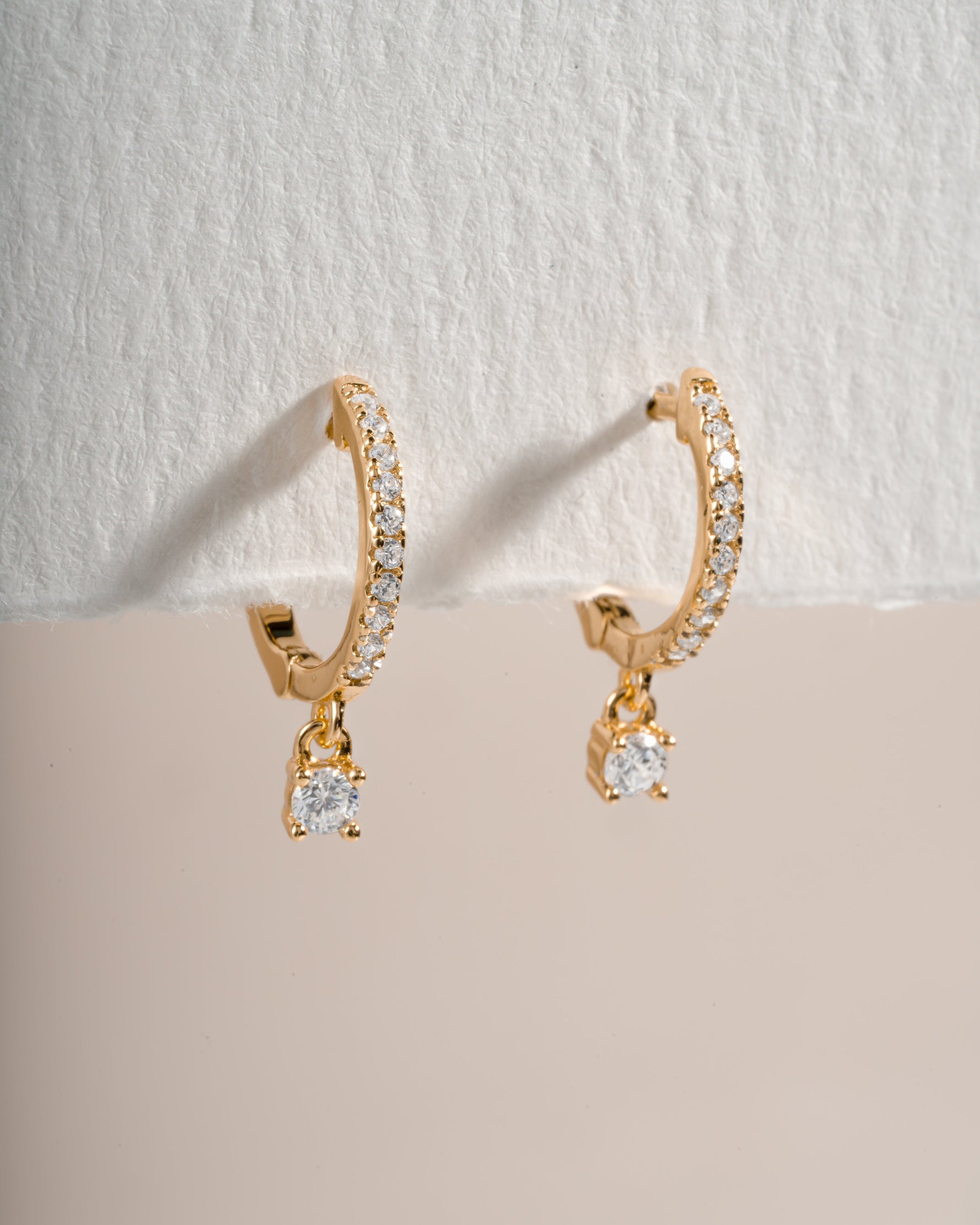 Close-up of gold Pavé Charm Huggies earrings by Sami Jewels with sparkling pave detailing and small charm accents.