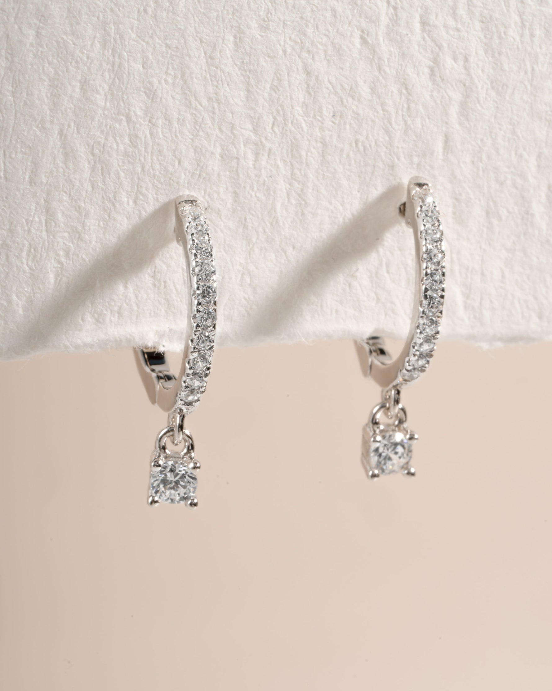 Sterling silver Pavé Charm Huggies earrings with sparkling pave design, angled view showcasing intricate craftsmanship.
