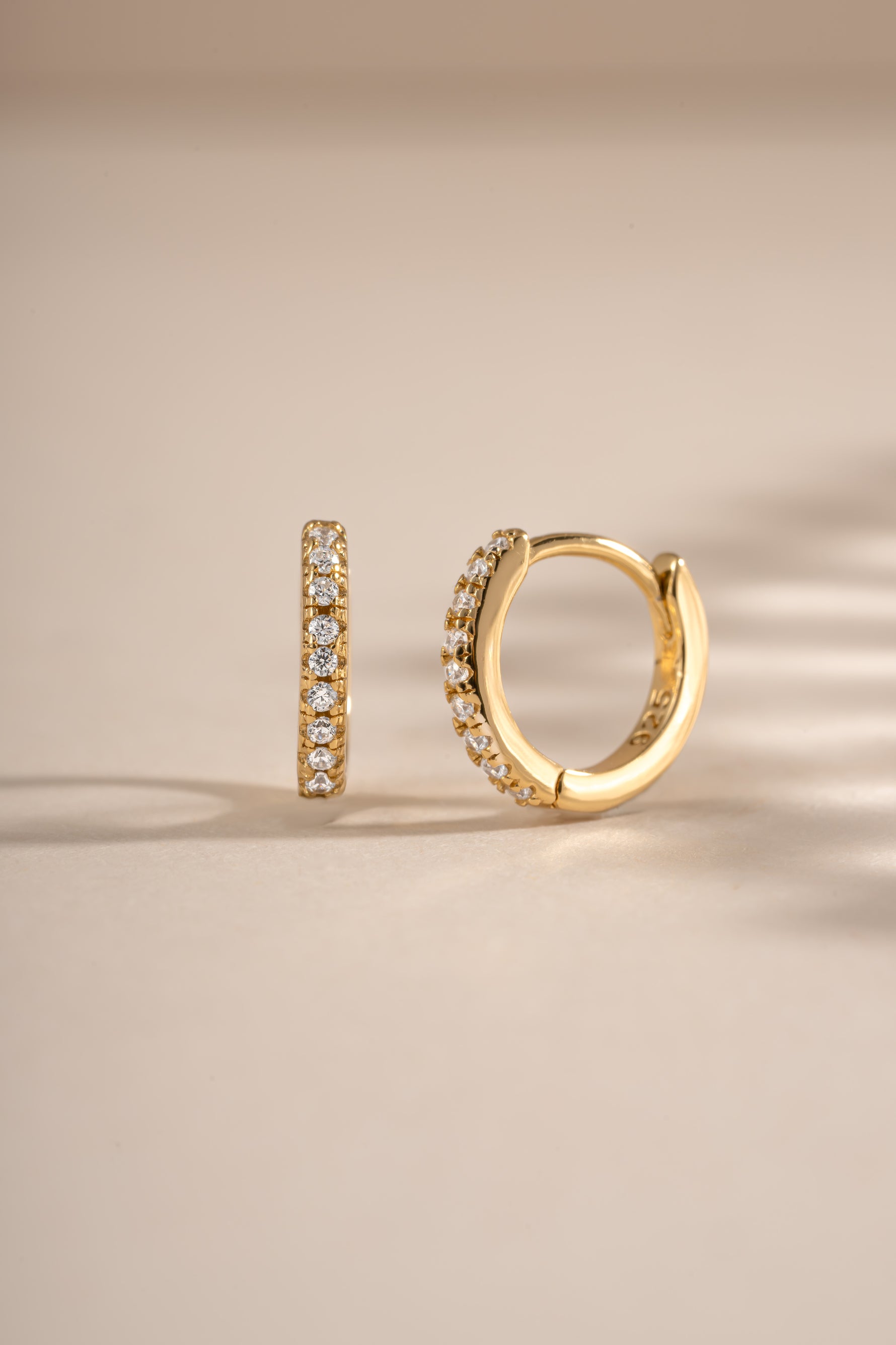 Close-up of 6mm gold CZ huggie earrings with pave diamond design by Sami Jewels.