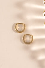Gold 6mm CZ huggie earrings by Sami Jewels featuring pave diamond accents, shown from a side view.