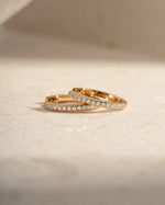 Gold 11mm Pavé Huggie Earrings by Sami Jewels with sparkling diamond accents, shown in close-up view.