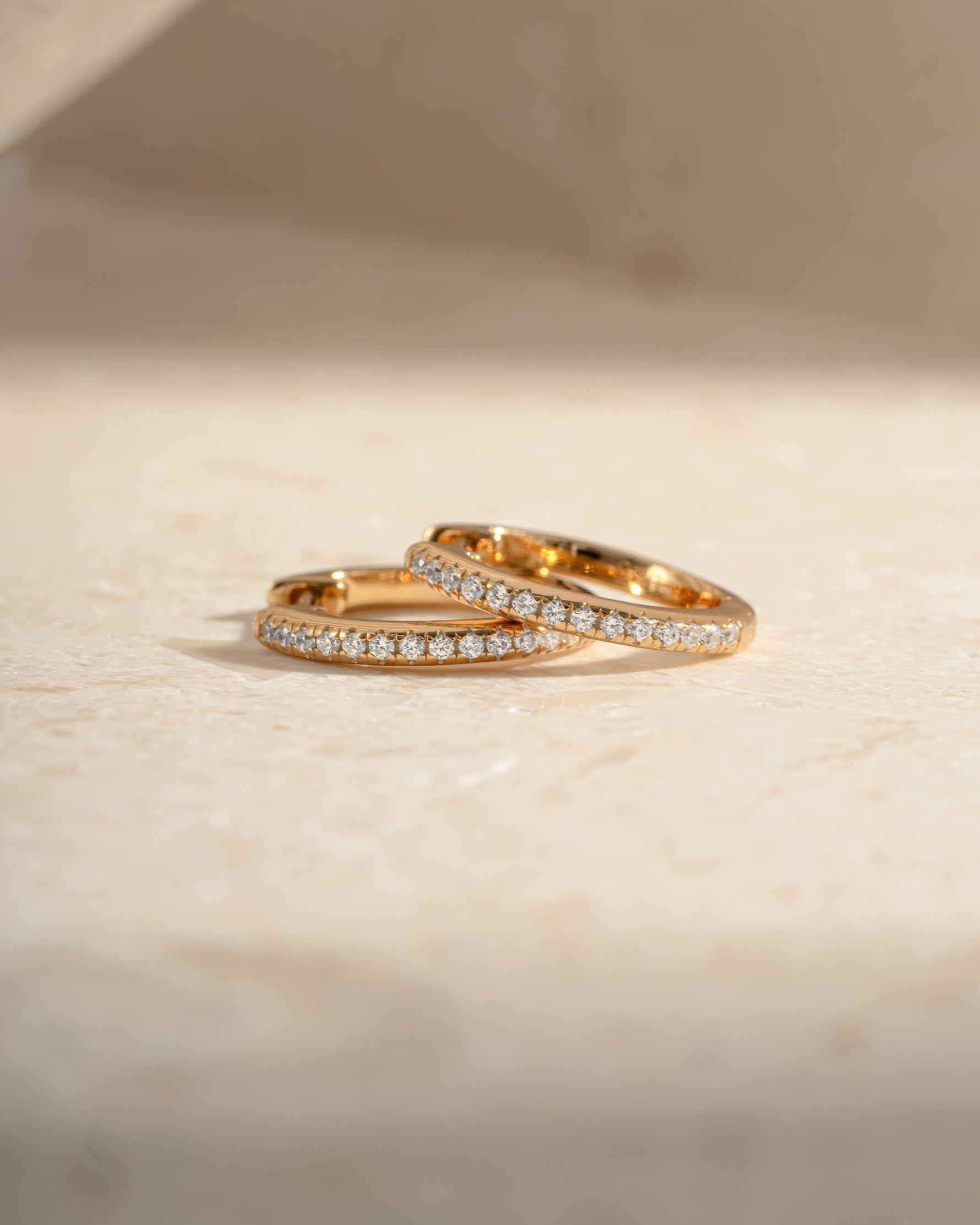 Gold 11mm Pavé Huggie Earrings by Sami Jewels with sparkling diamond accents, shown in close-up view.