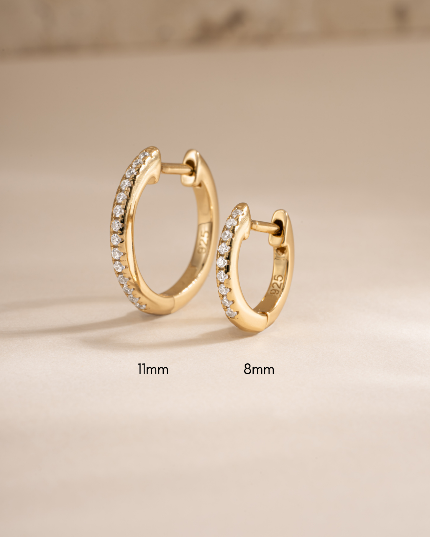 Gold 11mm pavé huggie earrings by Sami Jewels, shown in two different sizes with sparkling pavé detailing.