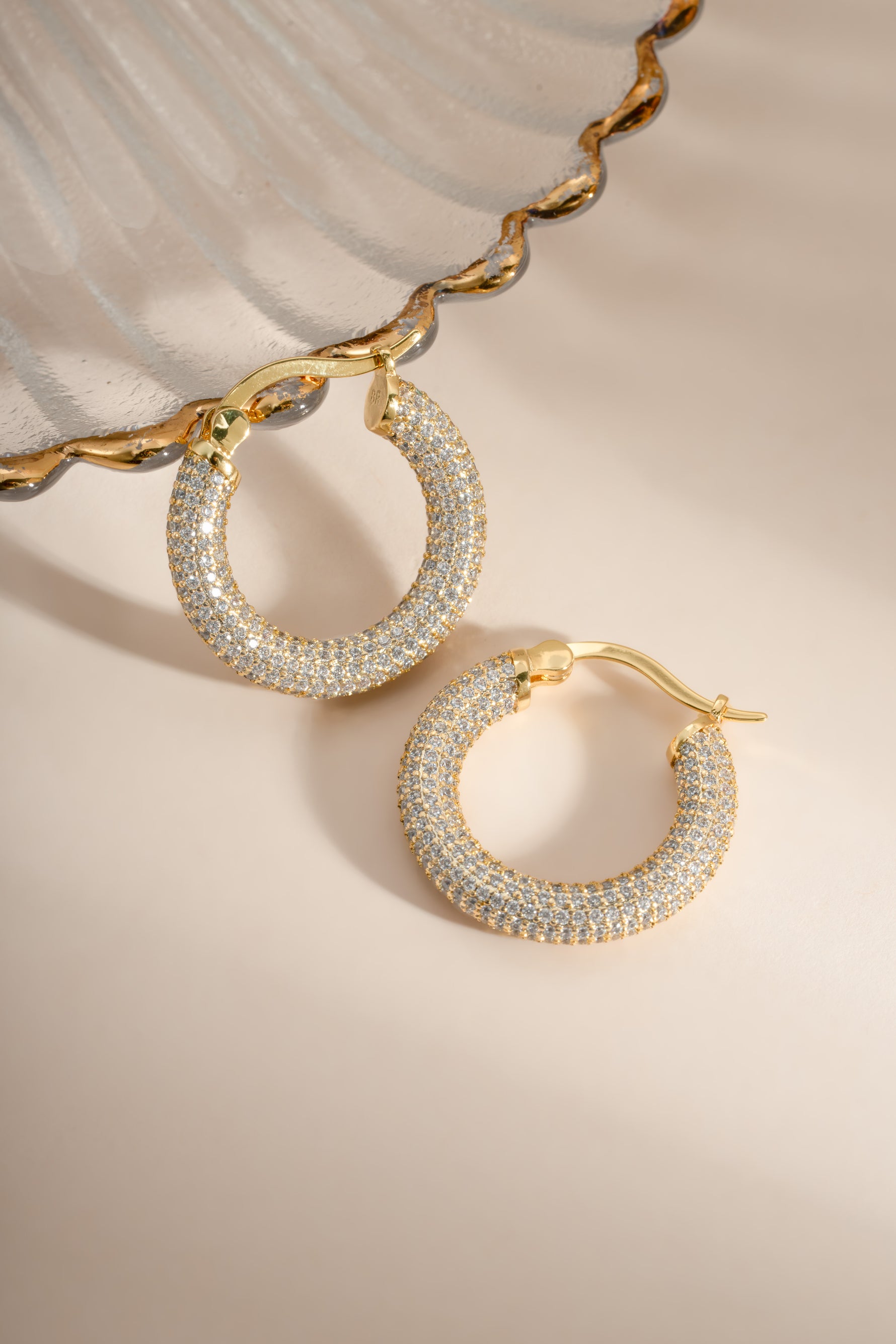 Close-up of gold pavé tube hoop earrings by Sami Jewels, showcasing their shiny, textured surface and classic hoop design.
