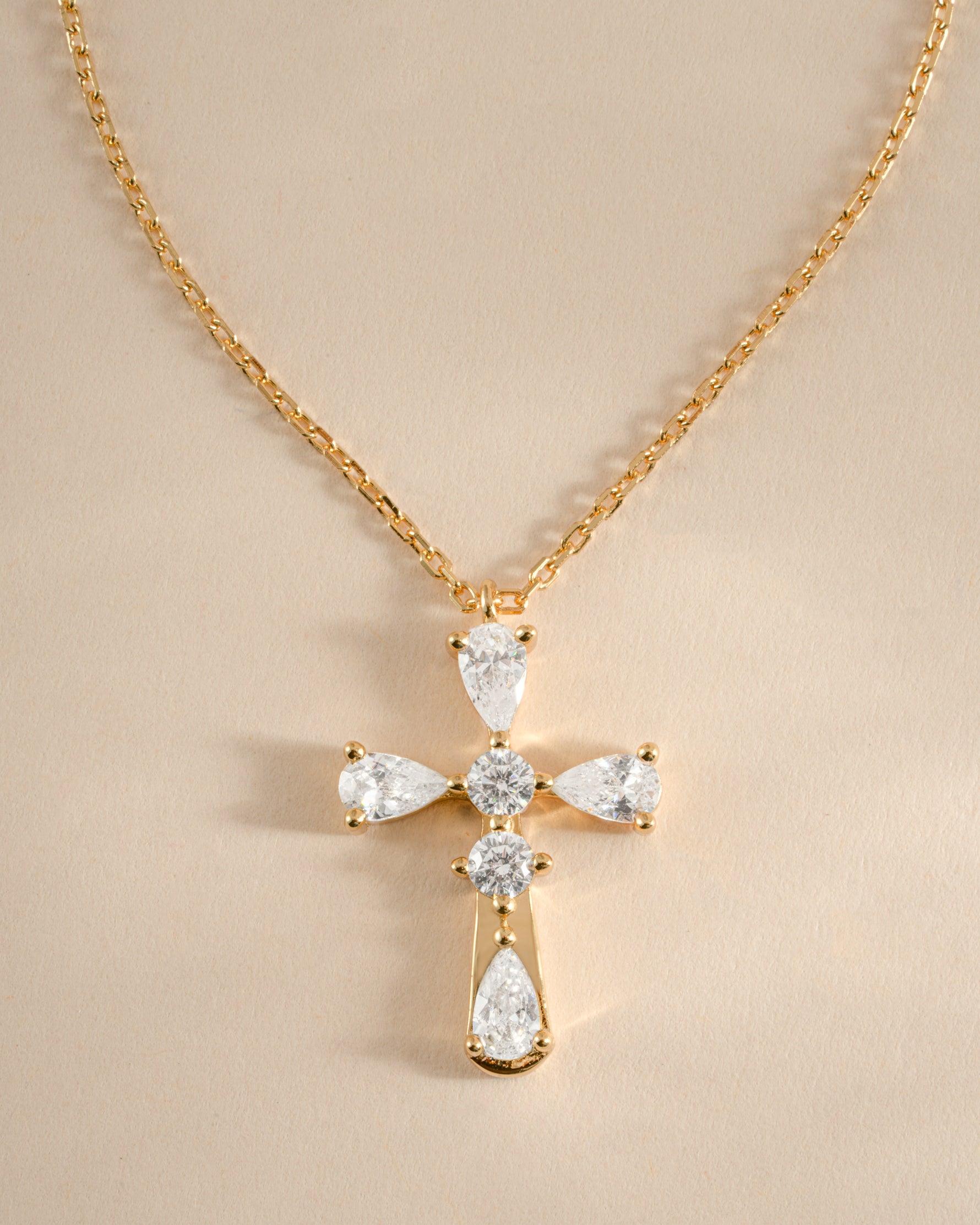 Close-up of Sami Jewels gold pear-cut cross necklace showcasing detailed craftsmanship on a chain.