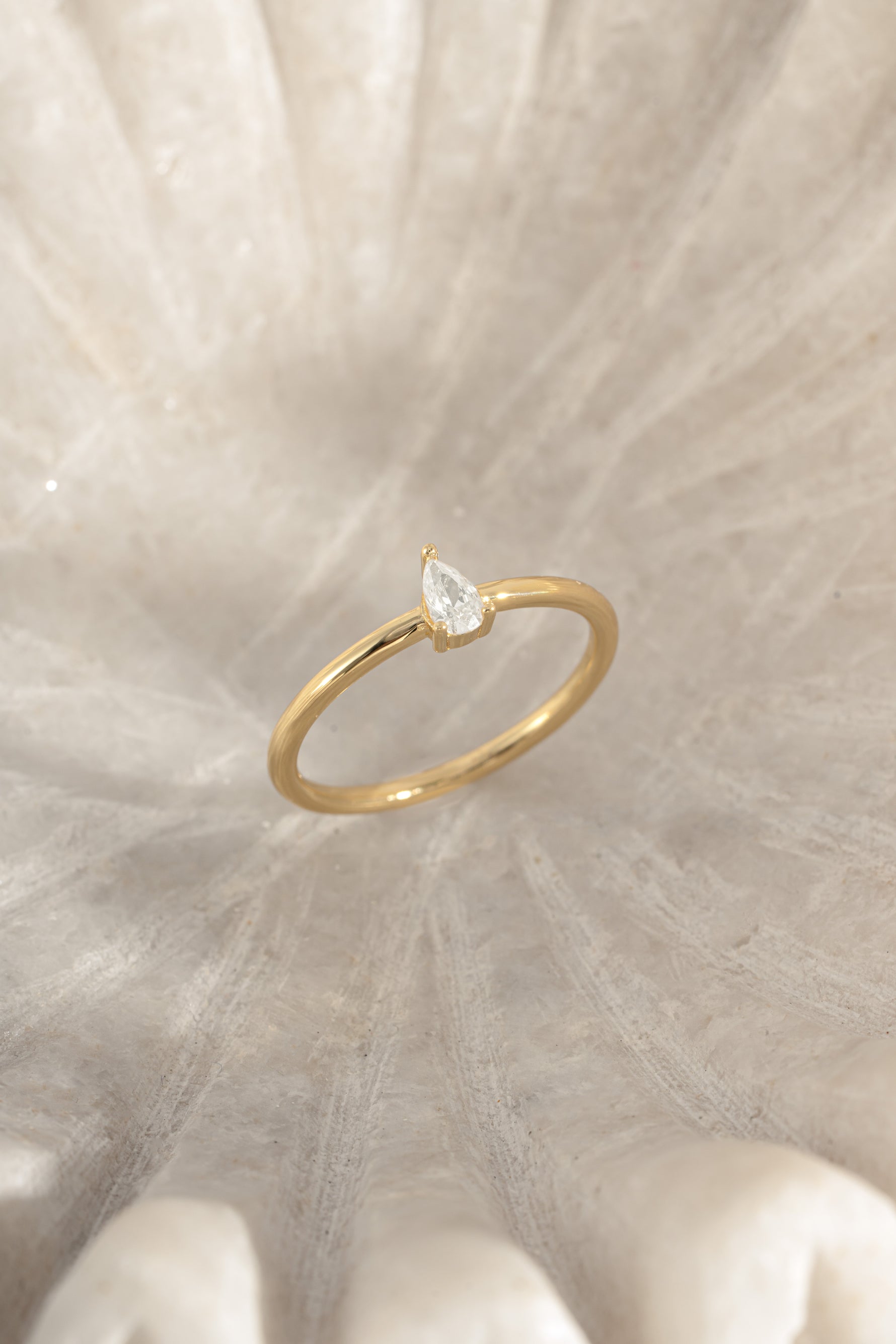 Gold pear-shaped ring from Sami Jewels, shown at an angled view highlighting its elegant gemstone cut and sleek design.