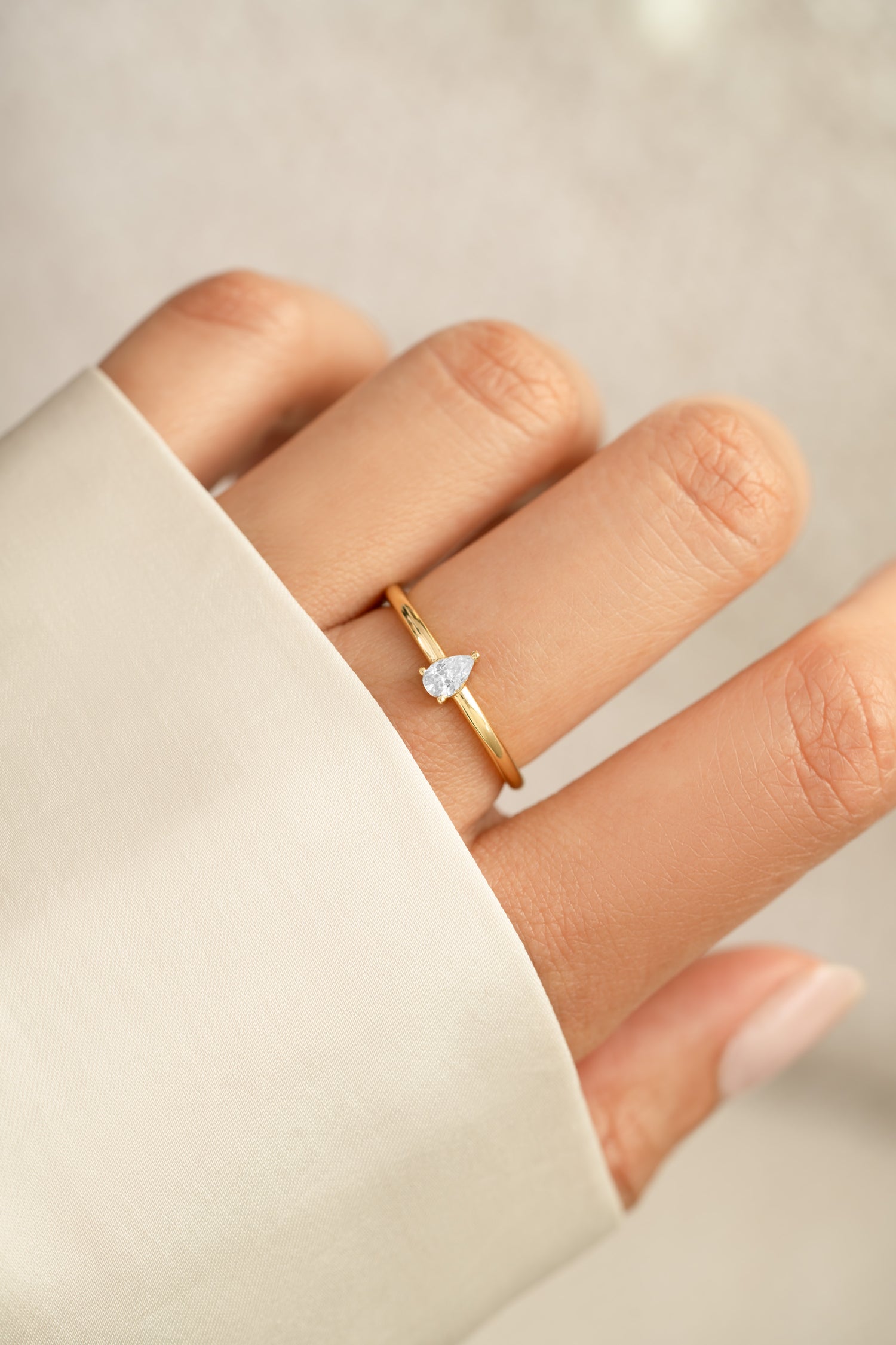 Gold pear-shaped ring from Sami Jewels featuring a sleek, elegant design on a model's hand.