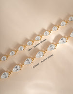 Two gold tennis bracelets with pear-cut clear stones, one labeled 'Mini - 3x4mm stones' and the other 'Classic - 4x6mm stones', displayed on a warm beige background.