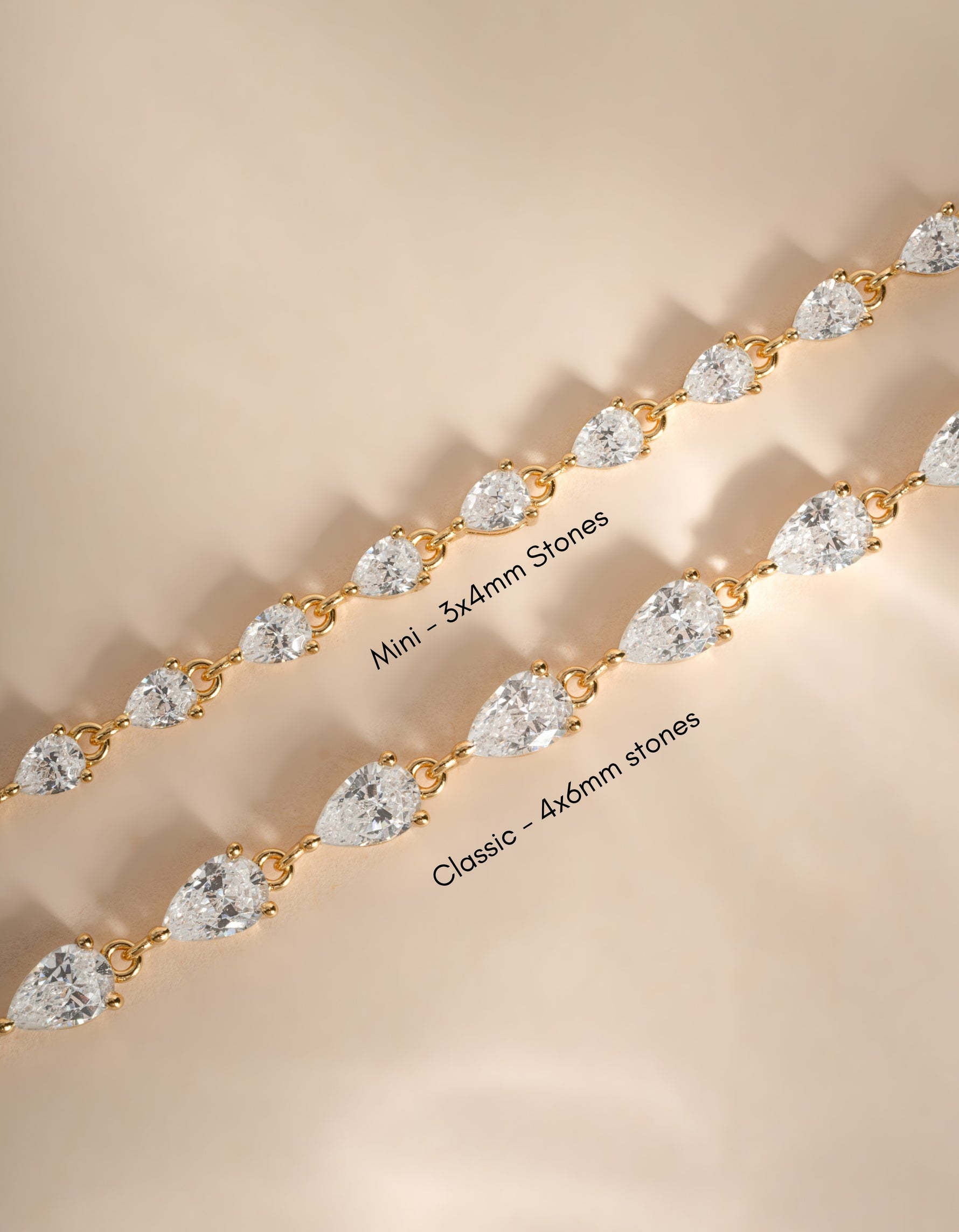 Two gold tennis bracelets with pear-cut clear stones, one labeled 'Mini - 3x4mm stones' and the other 'Classic - 4x6mm stones', displayed on a warm beige background.
