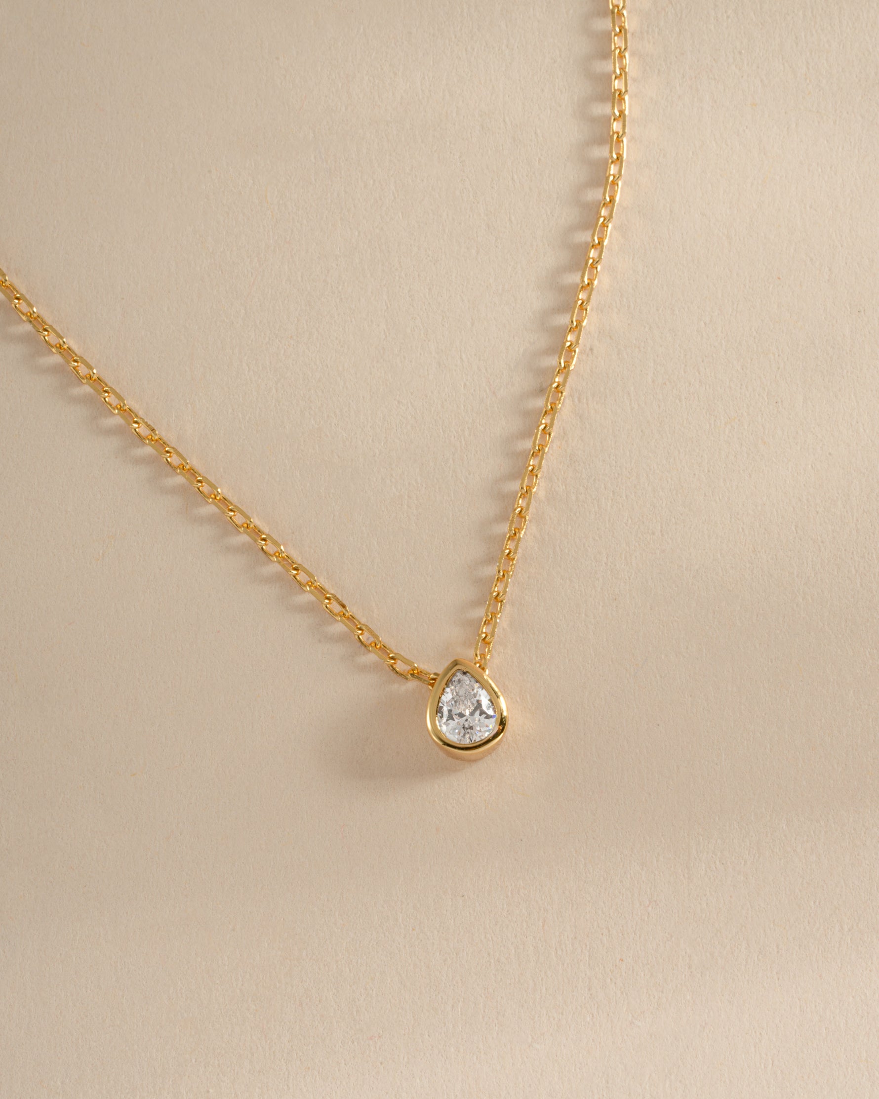 Close-up of Sami Jewels tear drop pendant necklace featuring a sparkling pear-shaped diamond on a gold chain.
