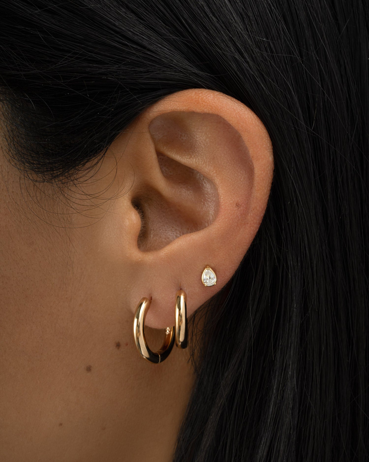 Gold tiny pear-shaped stud earrings by Sami Jewels, close-up of small, elegant pearl-shaped earrings on a model.