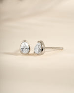 Sterling silver Tiny Pear Stud Earrings by Sami Jewels displayed from an angled view, showcasing their small pear shape and shiny finish.