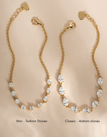 Two half tennis bracelet with pear stones  displayed side by side on a beige background, labeled 'Mini - 3x4mm Stones' and 'Classic - 4x6mm stones'. Each bracelet features a gold lobster clasp, an adjustable chain with a heart-shaped end, and a row of clear teardrop-shaped stones.