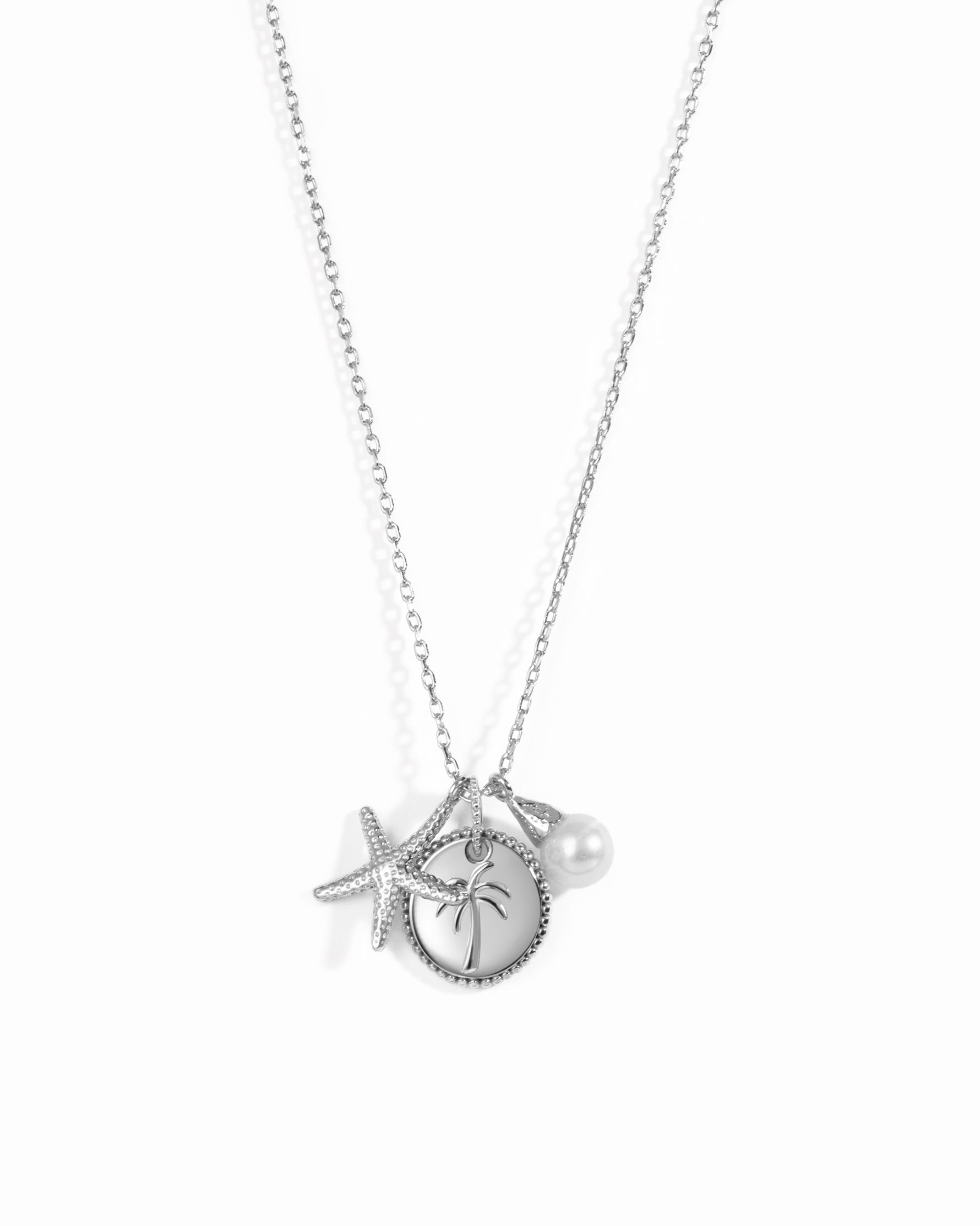 A silver-toned necklace featuring a starfish, a round pendant with a palm tree design, and a small pearl charm, displayed against a clean white background.