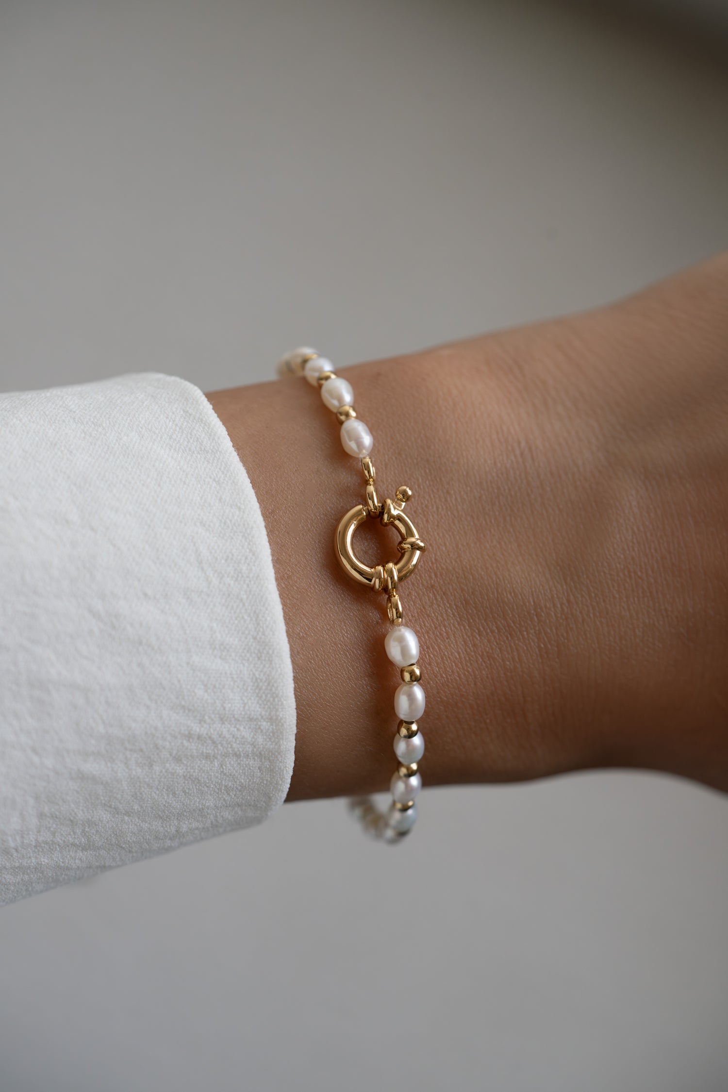 Beaded pearl bracelet by Sami Jewels featuring white pearls and gold accents on a model's wrist.