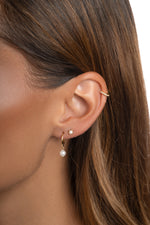 Gold Dainty Pearl Charm Hoop Earrings by Sami Jewels worn on a model, featuring small pearl charms on huggie-style hoops.