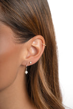Sterling silver dainty pearl charm hoop earrings by Sami Jewels worn by a model. Small, elegant pearl adorns each hoop.
