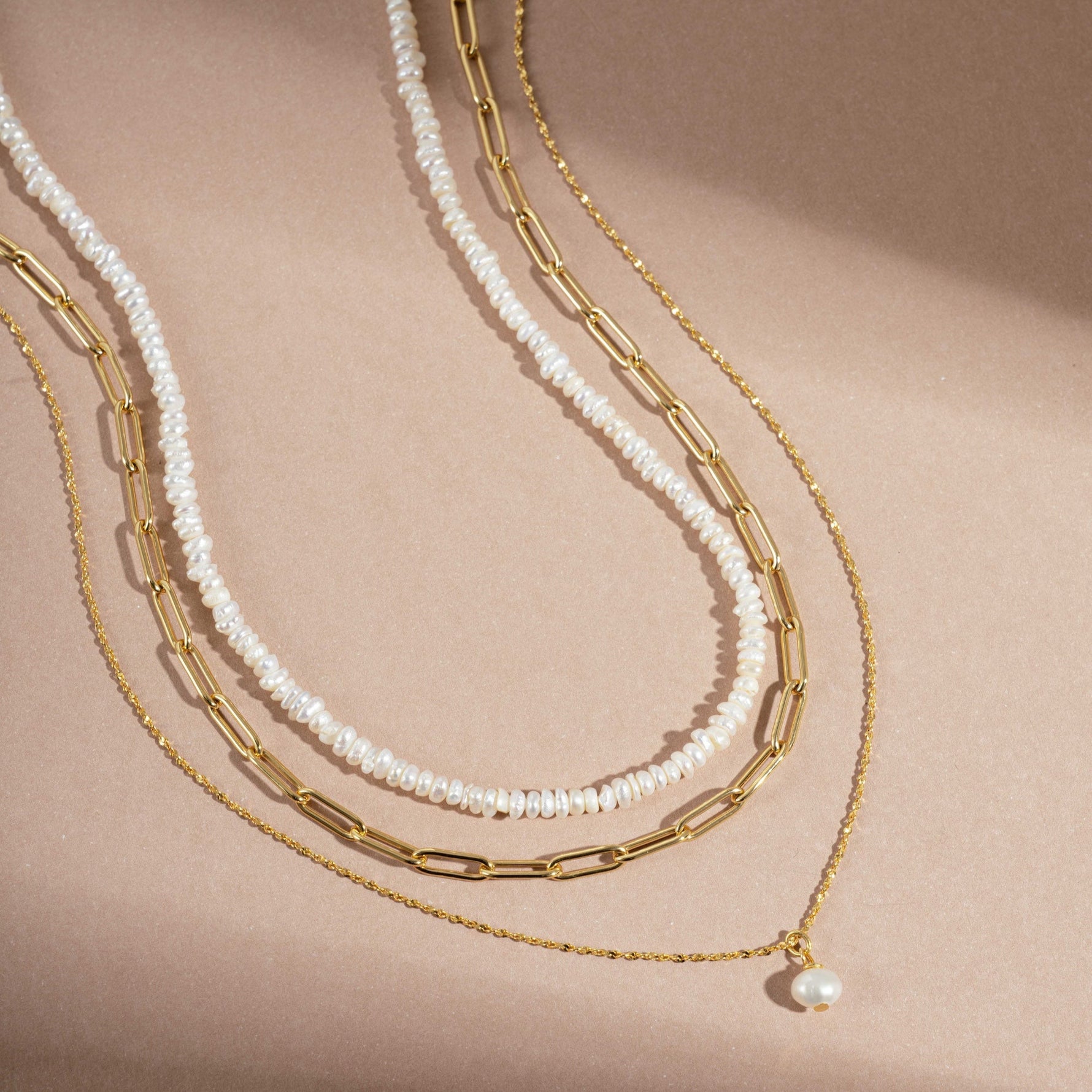 Sami Jewels Pearl Summer Necklace Stack flatlay, with pearl beaded necklace, paperclip necklace, and pendant pearl necklace in gold. 
