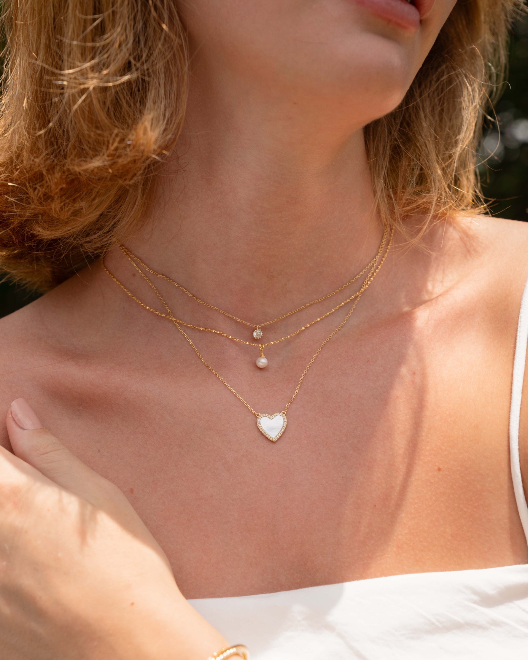 Gold pearl pendant necklace from Sami Jewels worn by a model, featuring a classic pearl charm on a delicate chain.