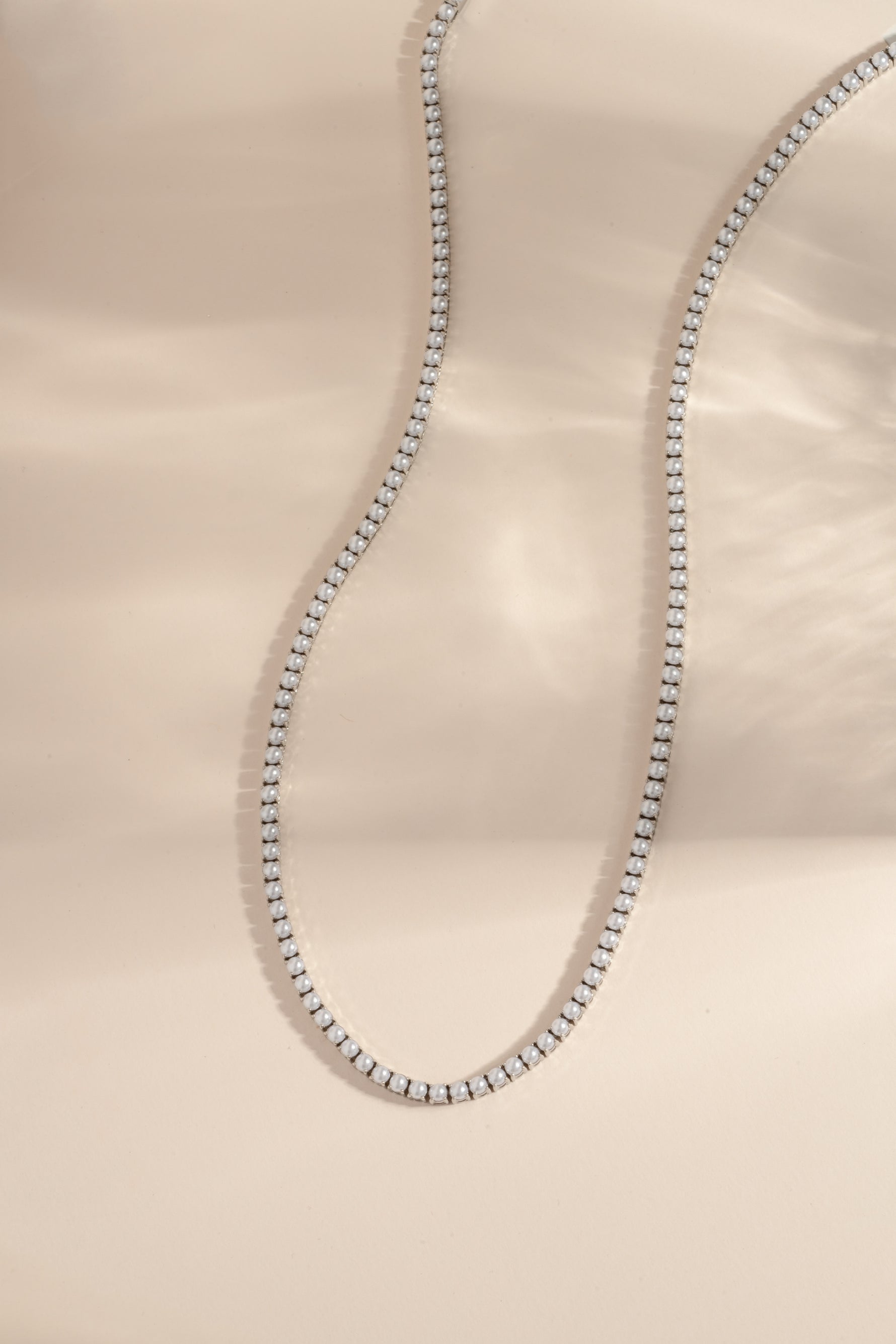 Sami Jewels SS Pearl Tennis Necklace with silver stainless steel chain and freshwater pearls, front view displaying elegant design.