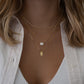 Model wearing halo emerald cut necklace on Cuban chain, with personal gold dog tag necklace for women.