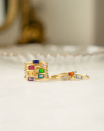 Gold rings with colorful gemstones on a white surface