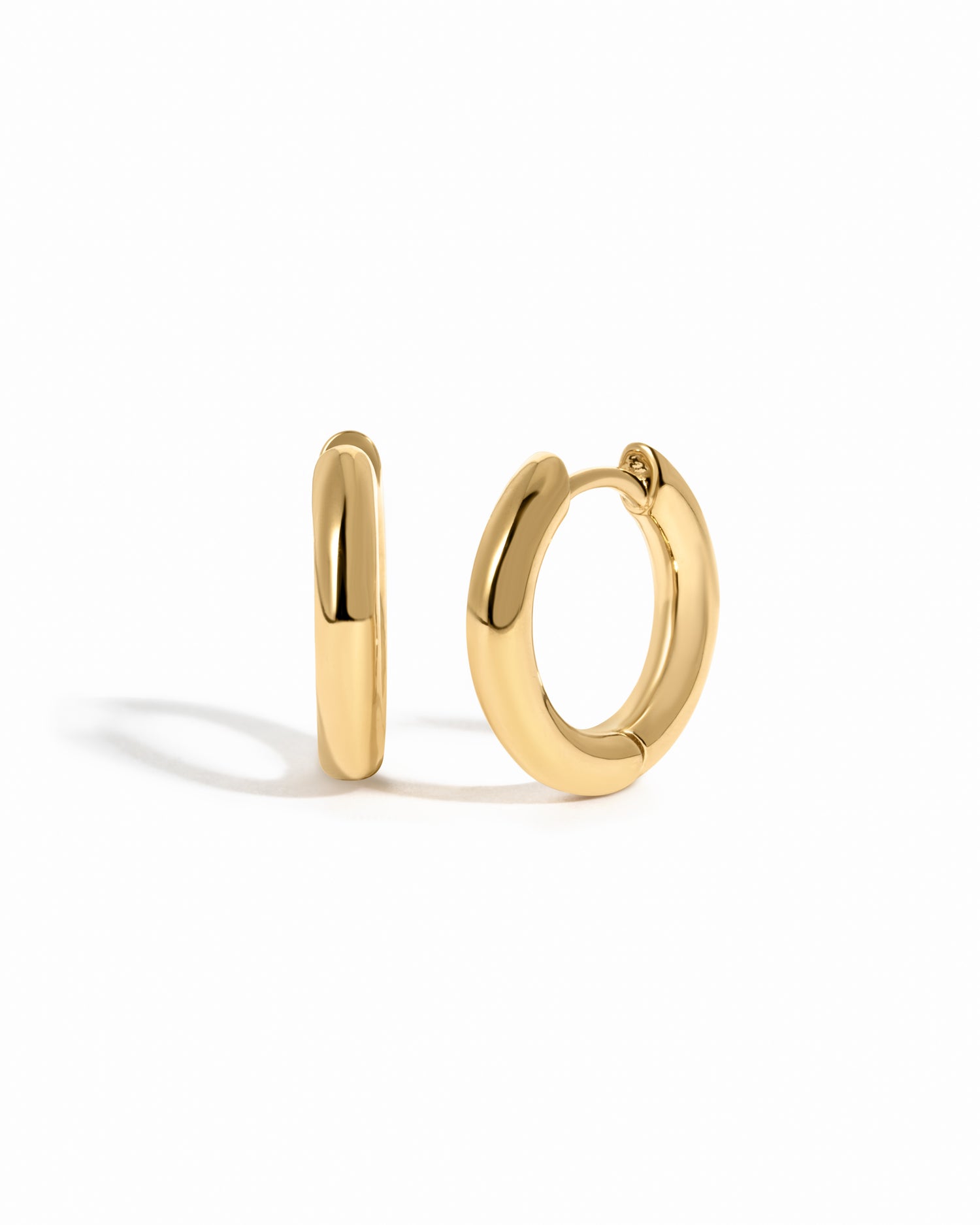 plain minimalist huggie hoops in gold in 10mm on a white background