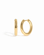plain minimalist huggie hoops in gold on a white background