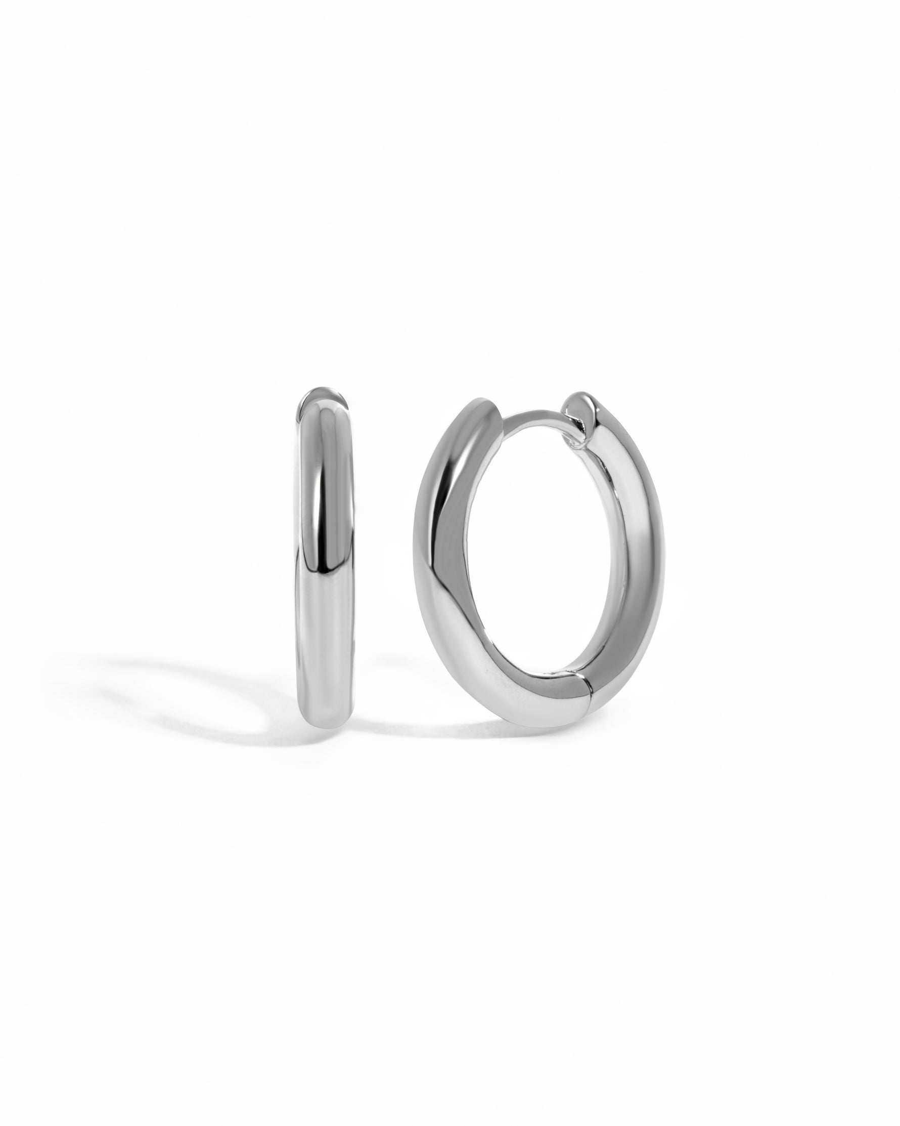 plain minimalist huggie hoops in sterling silver on a white background