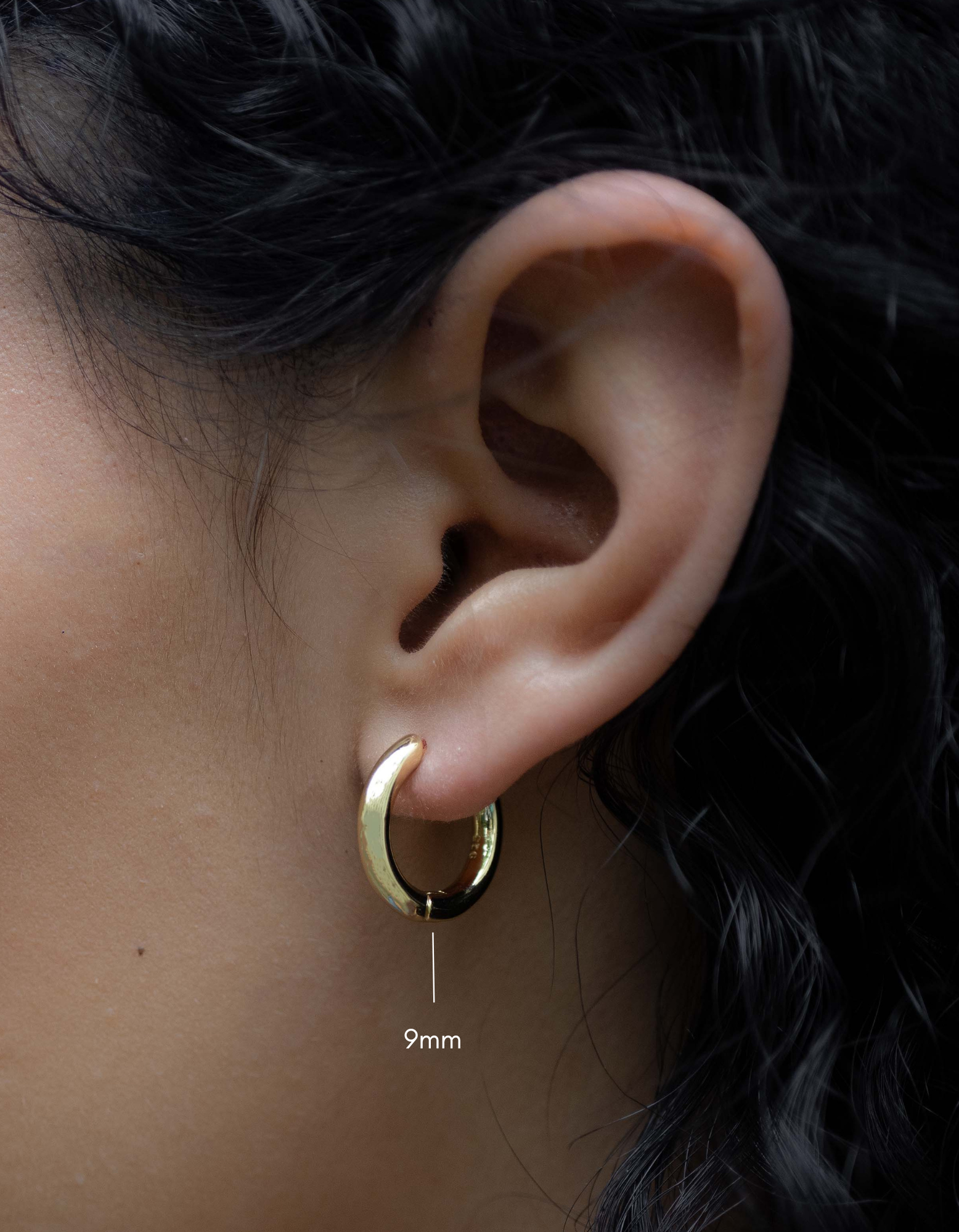 plain huggie hoop earring in 9mm in gold on models ear