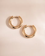 plain huggie hoop earring in gold in 9mm on simple background