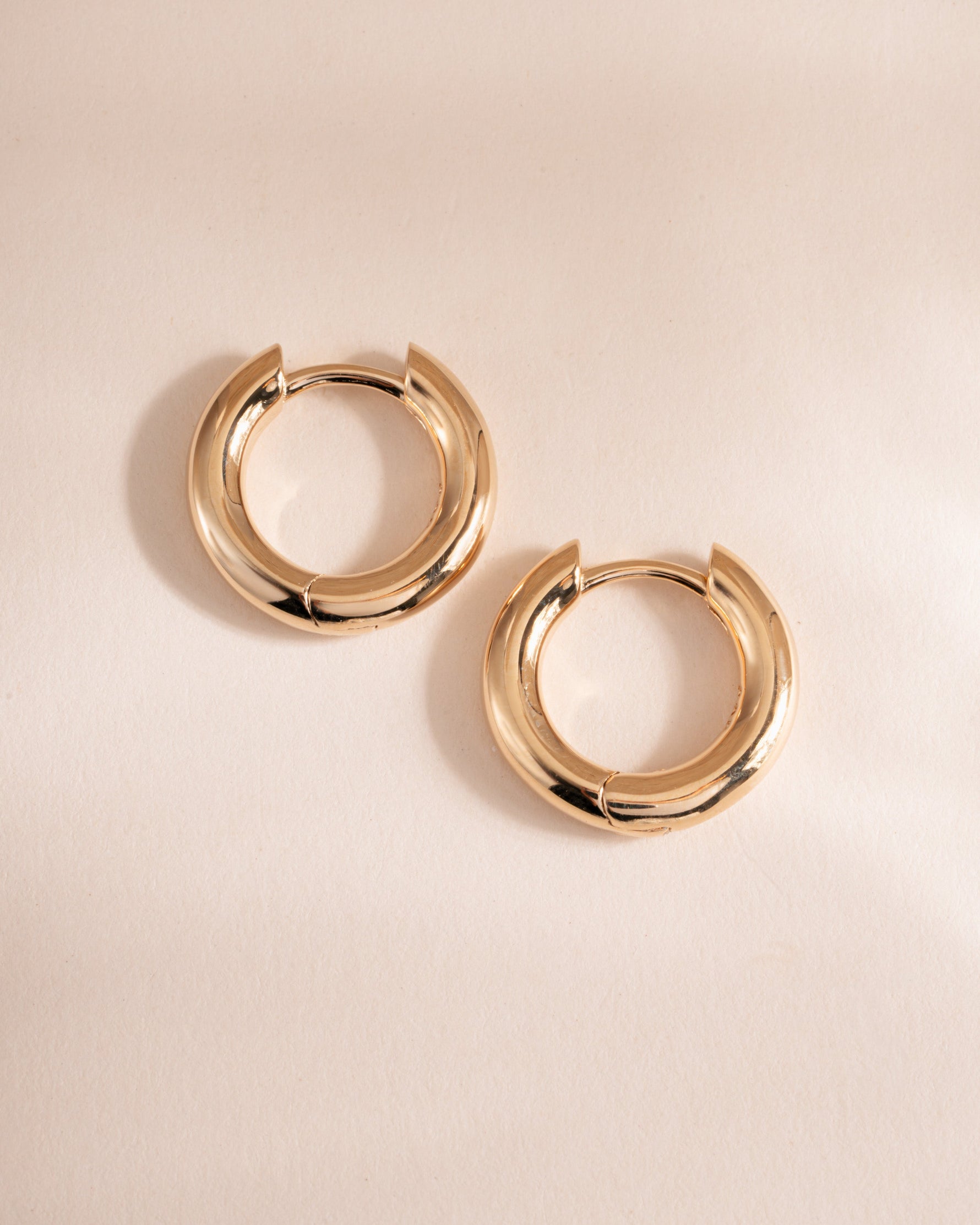 plain huggie hoop earring in gold in 9mm on simple background