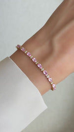 Movement of gold pink cubic zirconia tennis bracelet with alternating round diamonds on wrist.