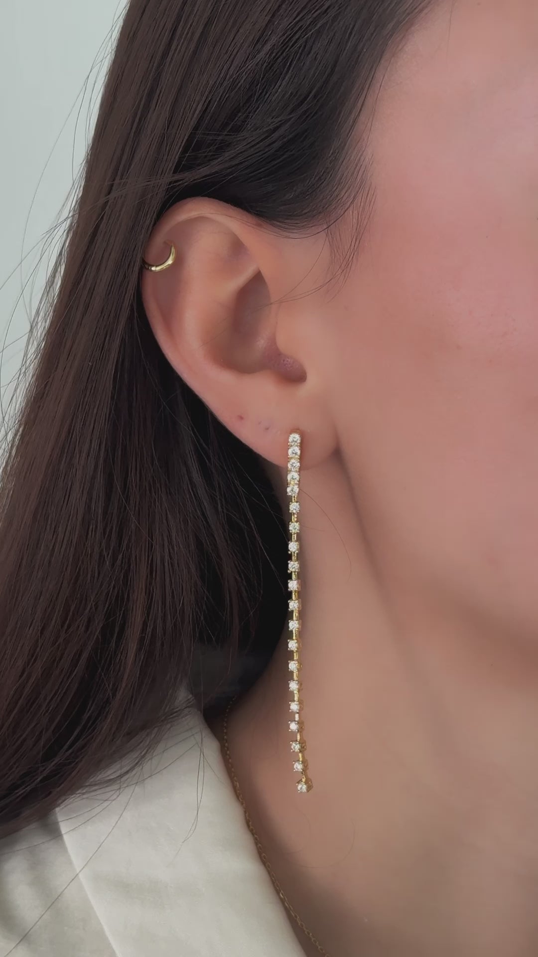 video of model wearing long earrings in gold featuring shimmering diamonds that feel smooth yet structured, perfect as statement earrings.