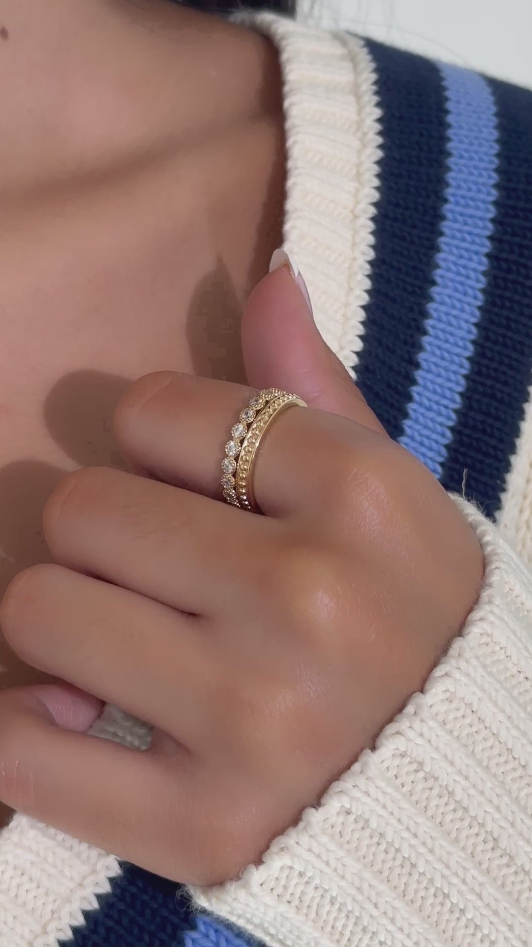 Video of model wearing dainty gold diamond ring set with cozy white and blue striped sweater