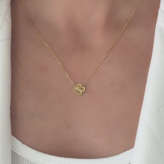 a close up video of chain necklace with four leaf clover pendant in gold. 