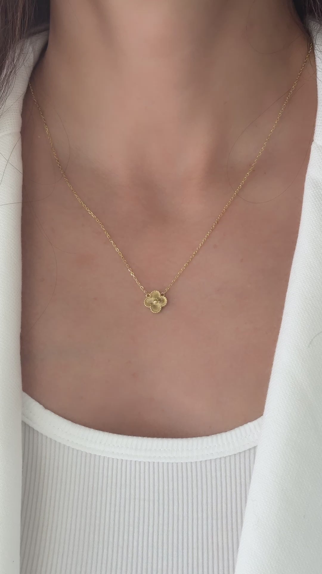 a close up video of chain necklace with four leaf clover pendant in gold. 