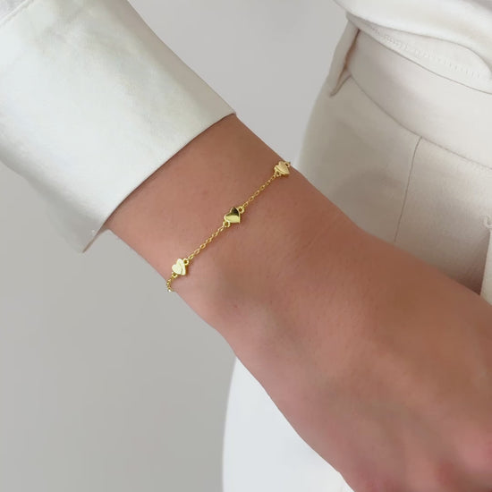 video of the gold charm bracelet styled solo on a wrist, complementing a casual chic outfit with a touch of elegance.