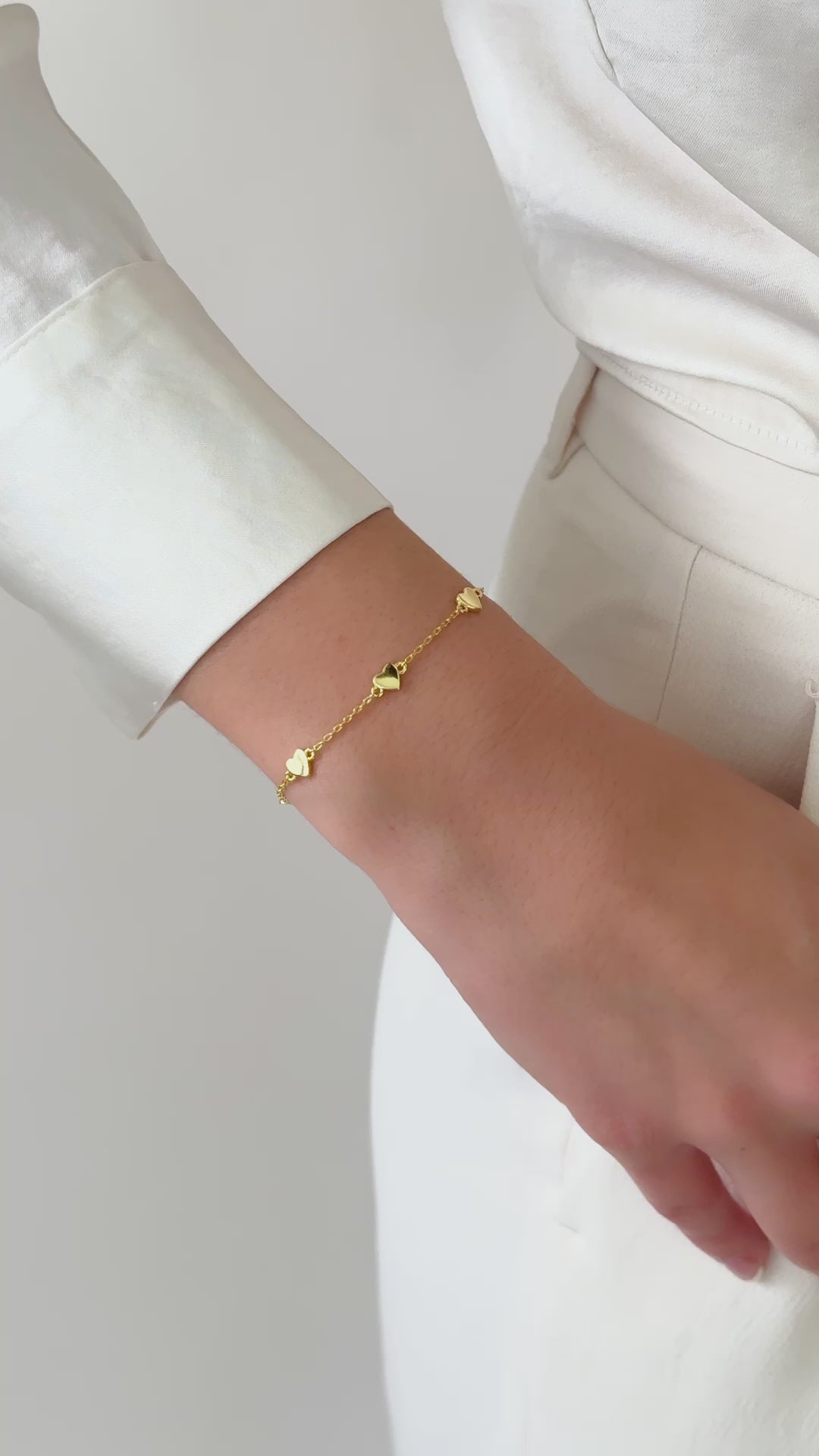 video of the gold charm bracelet styled solo on a wrist, complementing a casual chic outfit with a touch of elegance.